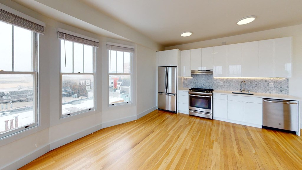 an empty kitchen with white cabinets and a wood floor