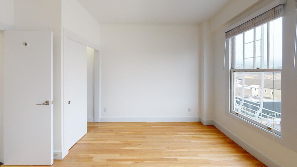 a room with white walls and a wood floor and a window