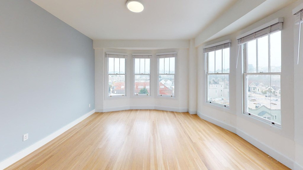 an empty living room with windows and wood floors