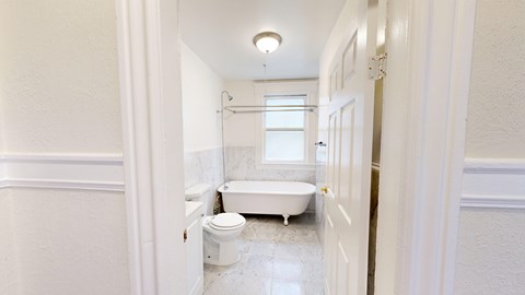A white bathroom with a tub, toilet and sink.