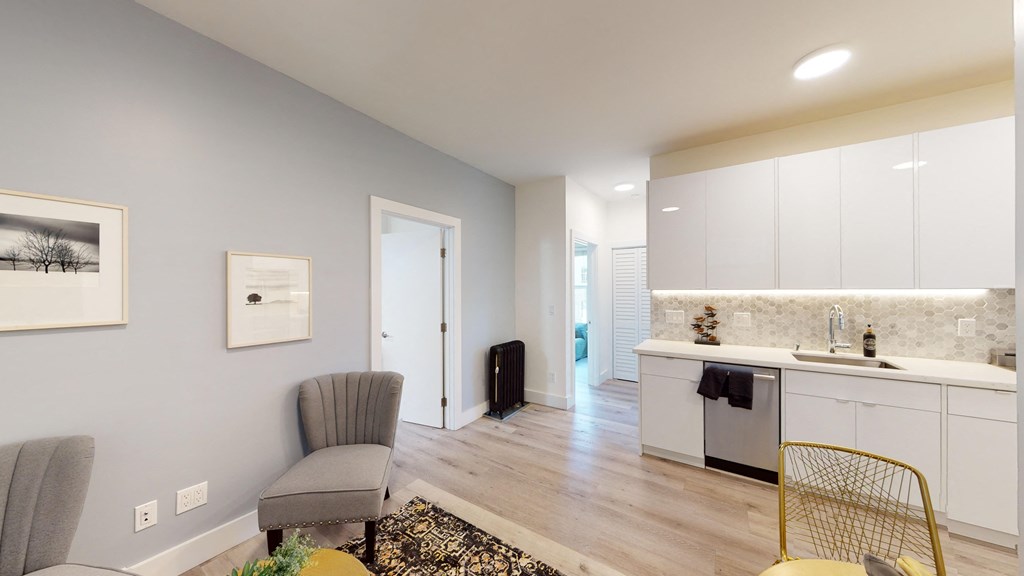 a living room with a kitchen and a door to a hallway