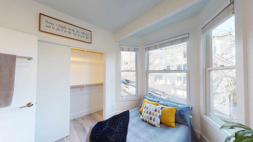 a bedroom with a large window and a bed with blue and yellow pillows