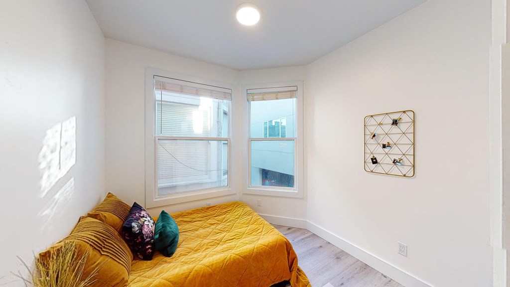 a bedroom with a couch and two windows