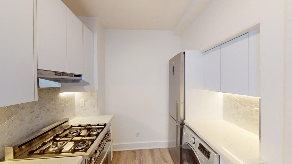 a kitchen with white cabinets and a stainless steel refrigerator