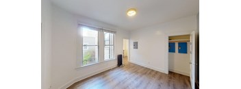 a living room with white walls and a large window and wood floors