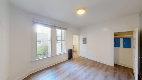 a living room with white walls and a large window and wood floors