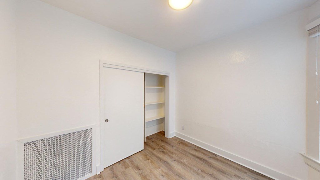 a bedroom with white walls and a closet with shelves