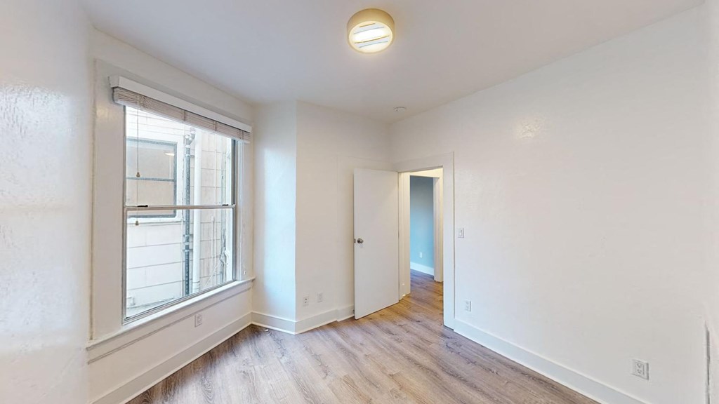 an empty living room with a large window and wood floors