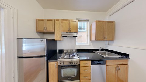 A kitchen with a stove, sink, and refrigerator.