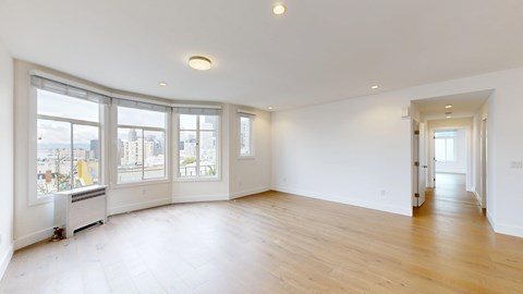 A spacious room with a window overlooking a cityscape.