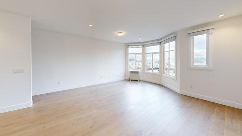 A large empty room with wooden floors and white walls.