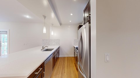 A modern kitchen with a stainless steel refrigerator and wooden flooring.