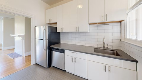 A kitchen with white cabinets and a black countertop.