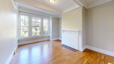 A room with wooden floors and a window overlooking trees.