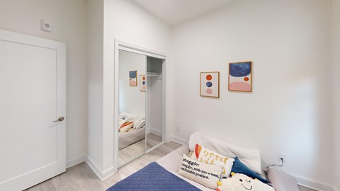 A bedroom with a bed, pillows, and pictures on the wall.