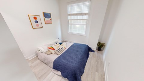 A bedroom with a bed covered in a blue blanket and two framed pictures on the wall.