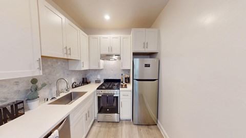 A kitchen with white cabinets and a marble backsplash.