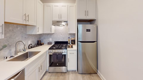 A kitchen with a stove, sink, and refrigerator.