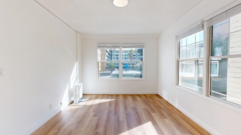 A room with wooden floors and two windows.
