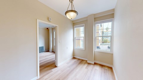 A room with a light hanging from the ceiling and a window with a view of a street.