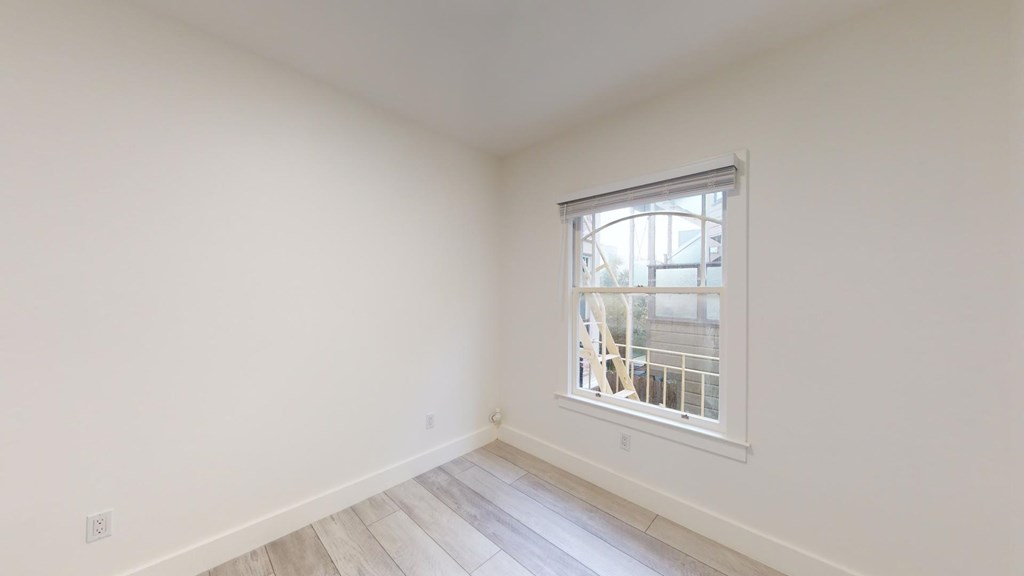 A room with a window and wooden flooring.