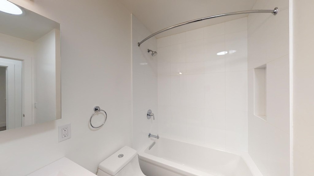 A white bathroom with a toilet, sink, and shower.