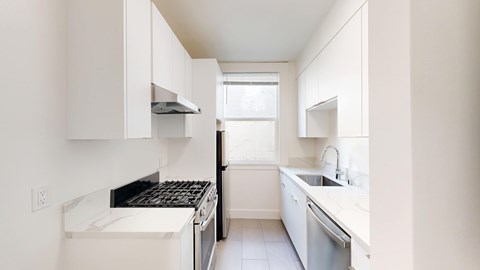 A white kitchen with a black stove top oven.