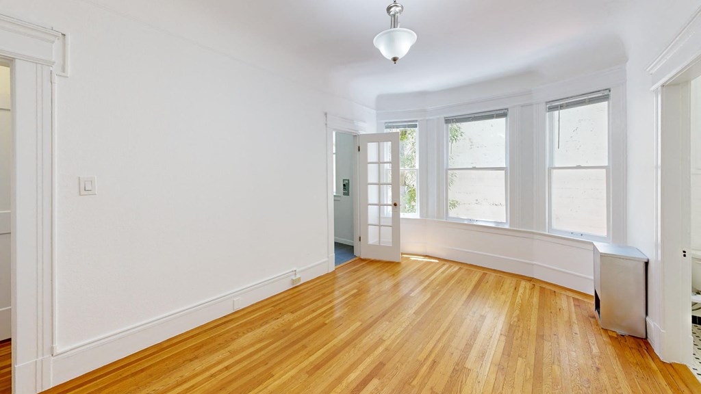 an empty living room with white walls and wood floors