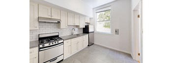 a white kitchen with white cabinets and a window