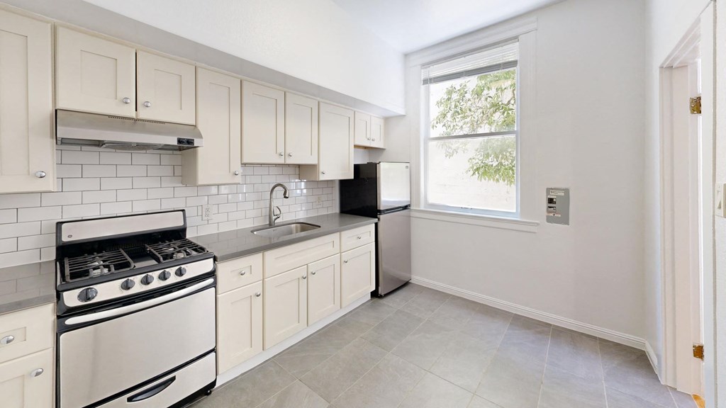 a white kitchen with white cabinets and a window