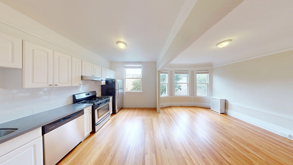 A kitchen with wooden floors and white cabinets.