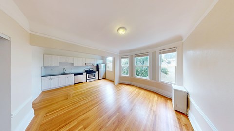 A spacious room with wooden floors and white walls.