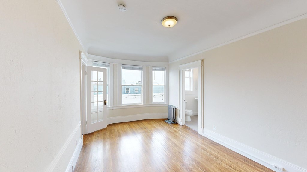 an empty living room with white walls and wood floors