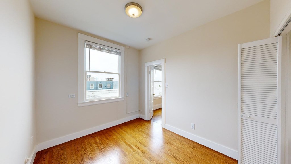 a living room with white walls and a window and wood floors