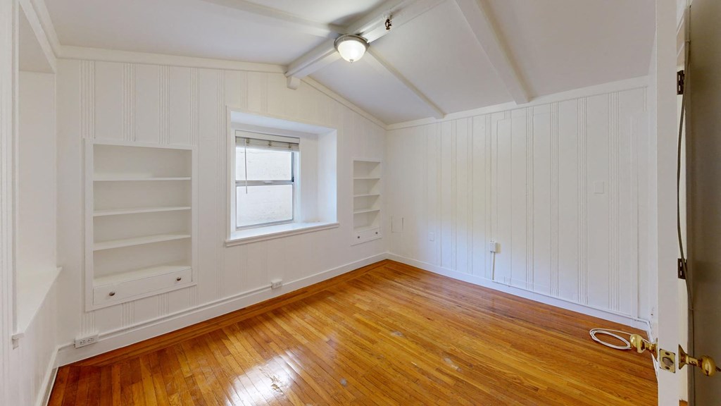 bedroom with white walls and a window and wooden floors