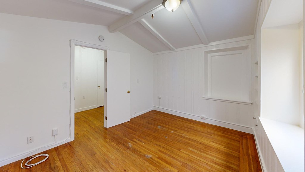 a bedroom with white walls and wood floors and a closet