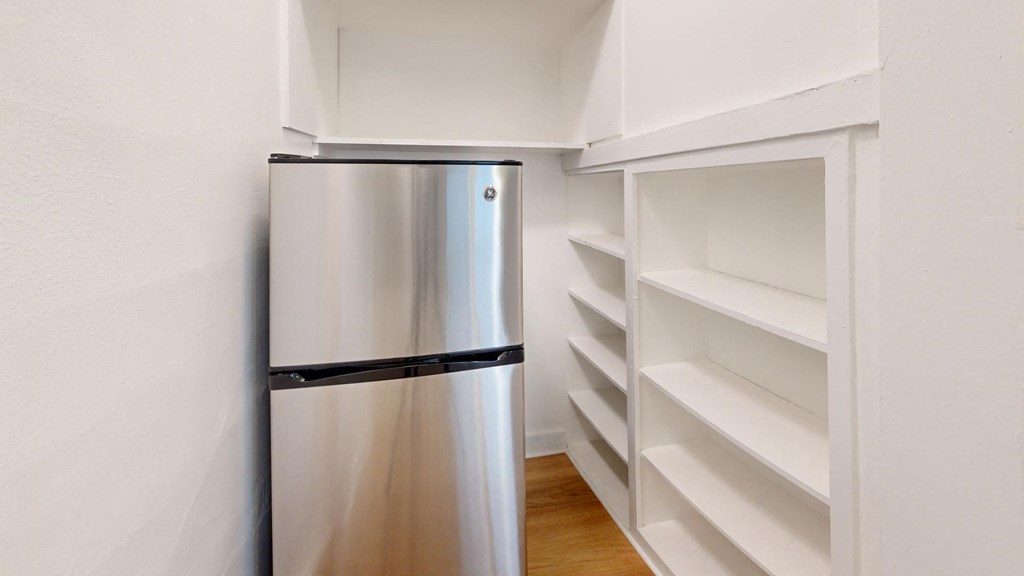 a kitchen with a stainless steel refrigerator and white shelves