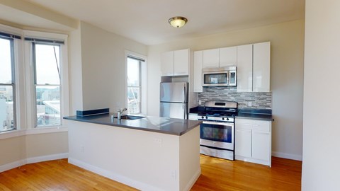 A kitchen with white cabinets and a wooden floor.