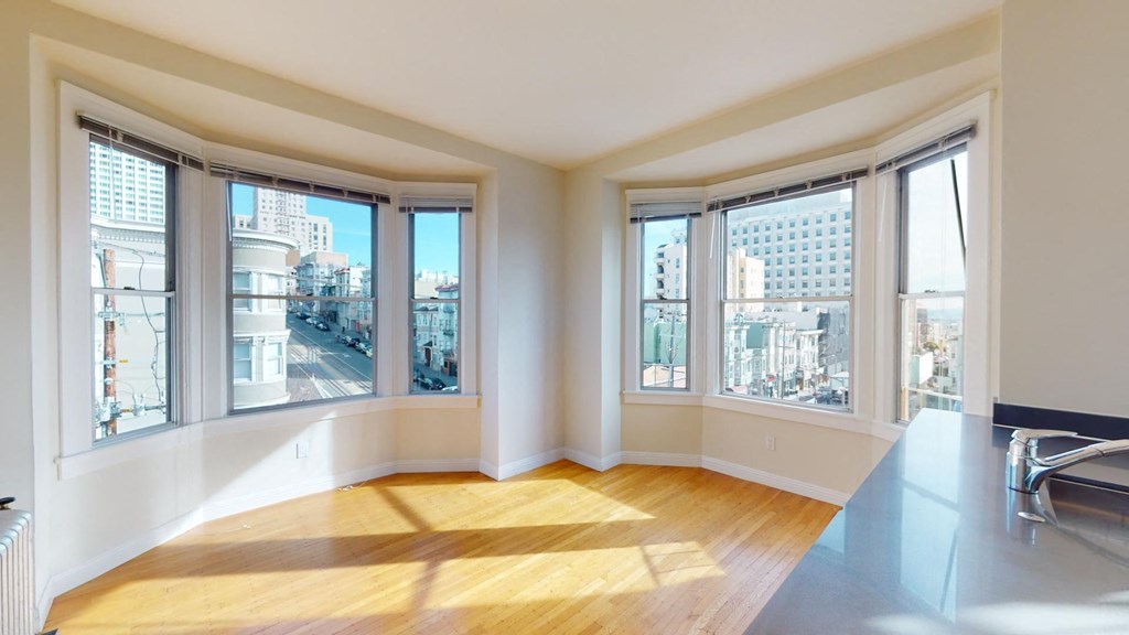 an empty living room with three windows and a city view