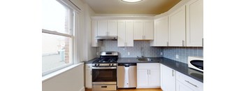a kitchen with white cabinets and a stove and a window