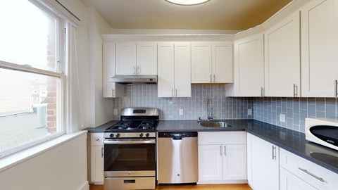 a kitchen with white cabinets and a stove and a window