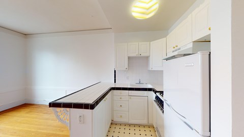 A kitchen with white cabinets and a black countertop.