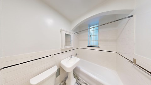 A white bathroom with a tub, sink, and mirror.