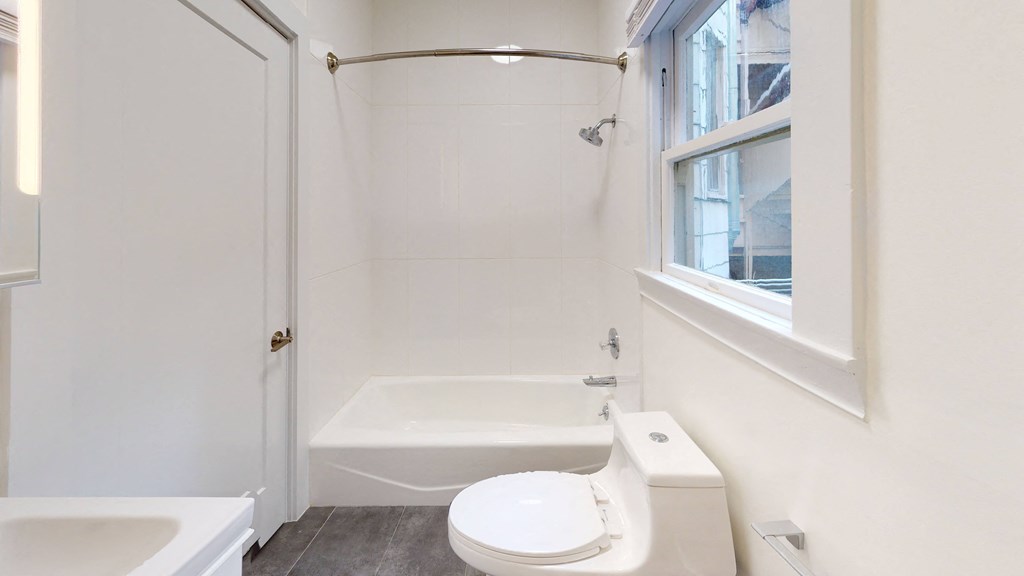 a bathroom with a white toilet and a tub and a window