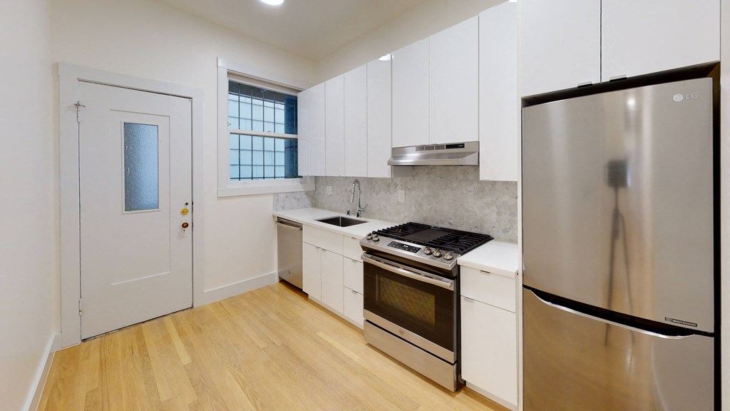 a kitchen with white cabinets and stainless steel appliances and a refrigerator