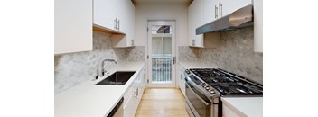 a kitchen with white cabinets and a door to a balcony