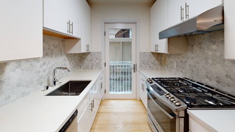 a kitchen with white cabinets and a door to a balcony