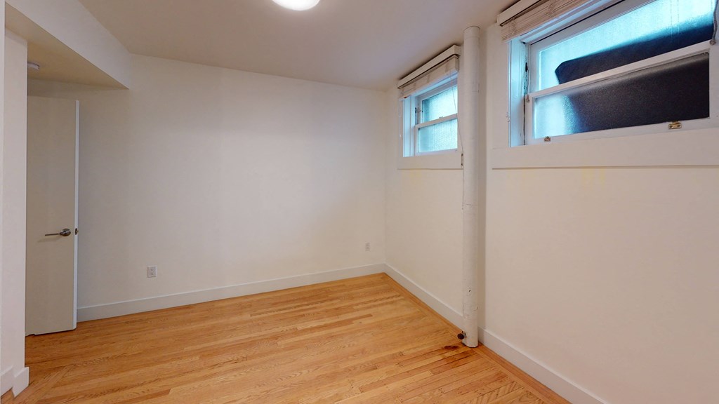 a bedroom with white walls and a window and a wooden floor