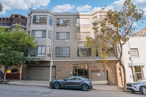 A grey car is parked in front of a building with a garage door.