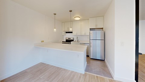 A kitchen with white cabinets and a refrigerator.